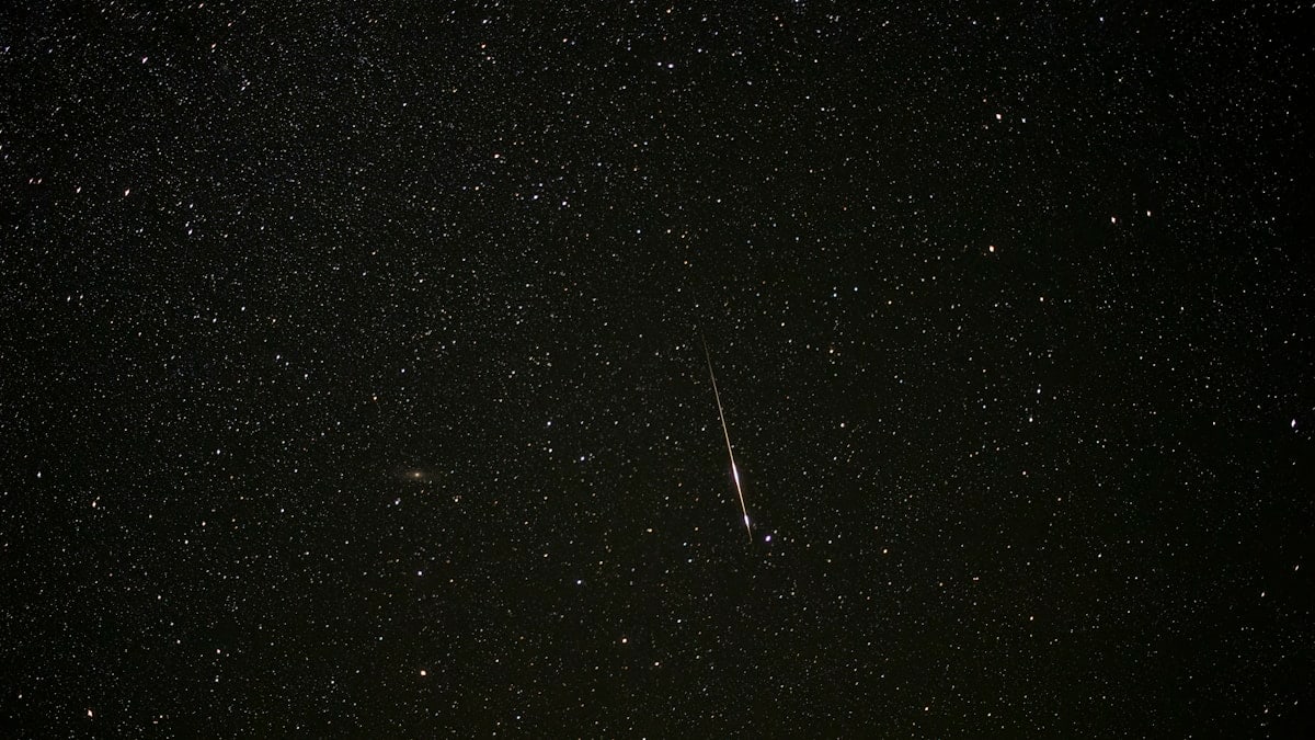 a dark sky with stars and a bright streak